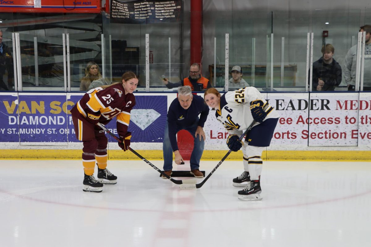 Wilkes President Dr. Greg Cant drops the puck with Sydney Bradley (left) and Rachel Morey (right)