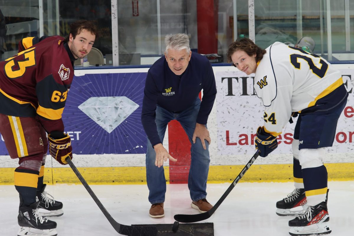 Wilkes President Dr. Greg Cant drops the puck with Sawyer Senio (left) and Max Cocchi (right).